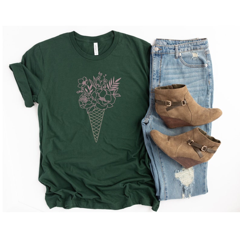 May include: A dark green t-shirt with a pink outline of a bouquet of flowers in an ice cream cone.