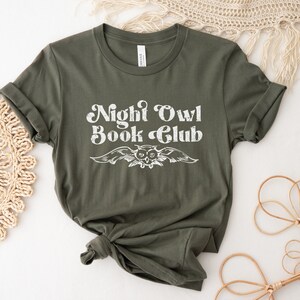 May include: A green t-shirt with the text "Night Owl Book Club" in white with a vintage owl graphic.