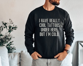 May include: Black sweatshirt with white text that reads "I have really cool tattoos under here, but I'm cold."