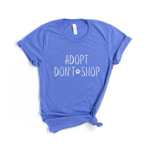 May include: A blue t-shirt with the text "Adopt Don't Shop" in white lettering with a paw print symbol.