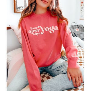 May include: A pink sweatshirt with the text "I am nicer after yoga" in white.