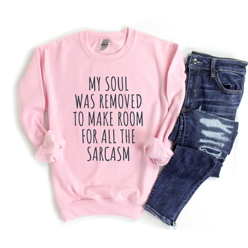 Może przedstawiać: R&oacute;żowa bluza z napisem "My soul was removed to make room for all the sarcasm" w kolorze czarnym.