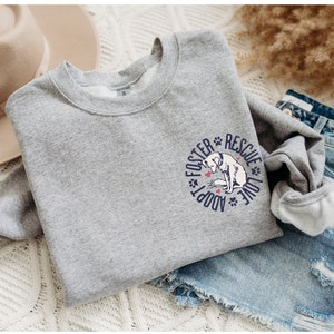 May include: Gray sweatshirt with a blue and white graphic of a dog with the text "Foster Adopt Rescue Love" in a circle.