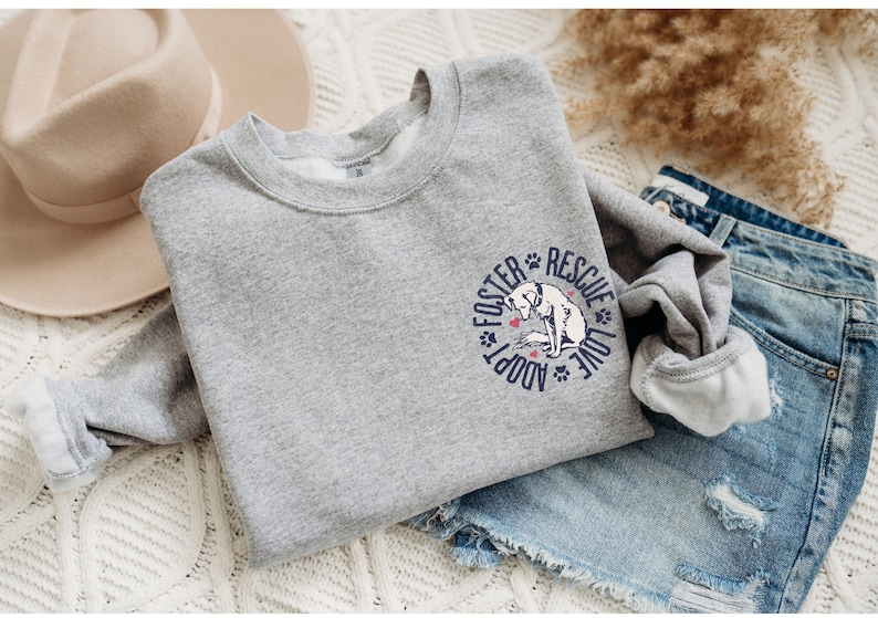 May include: Gray sweatshirt with a blue and white graphic of a dog with the text "Foster Adopt Rescue Love" in a circle.
