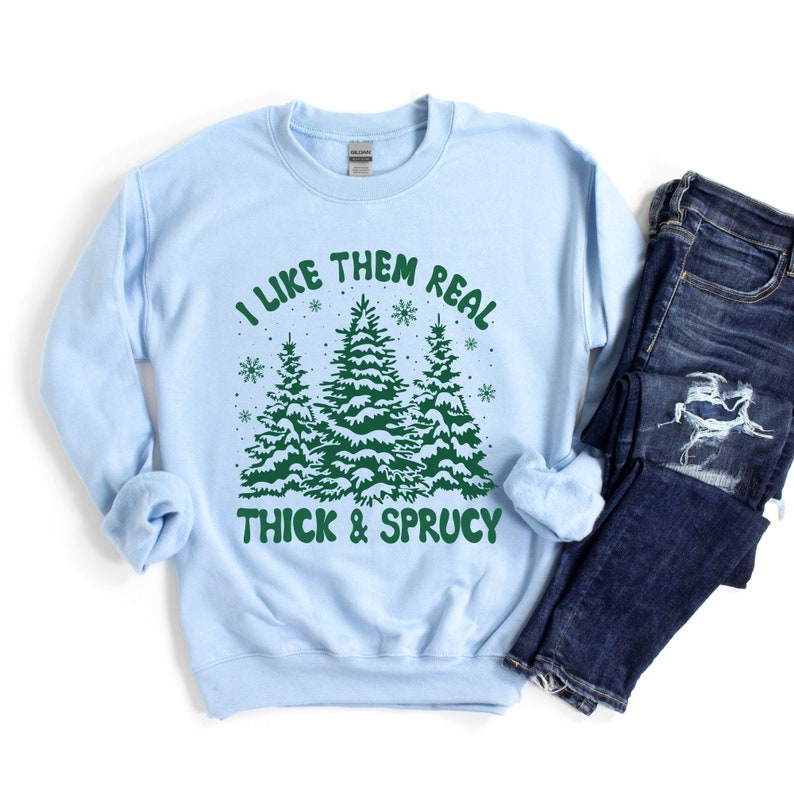 May include: Light blue sweatshirt with a green graphic of three Christmas trees and the text "I like them real thick & sprucy".