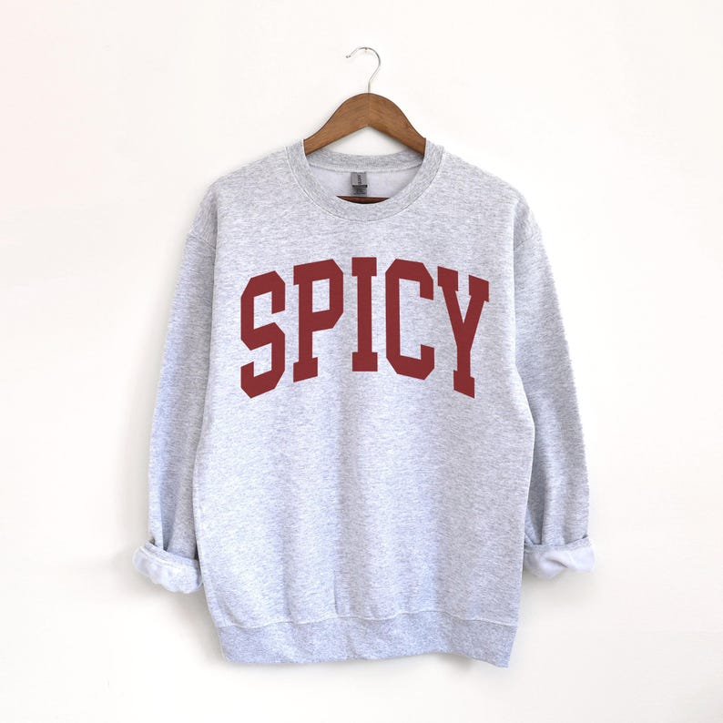Może przedstawiać: Szara bluza z nadrukiem "SPICY" w kolorze czerwonym na przodzie.