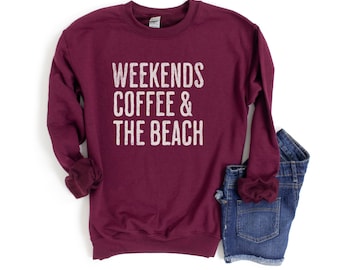 May include: A maroon sweatshirt with the text "Weekends Coffee & The Beach" in white.