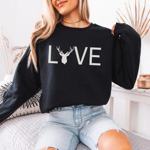 May include: Black sweatshirt with a white graphic of a deer head and the word "LOVE" on the front.
