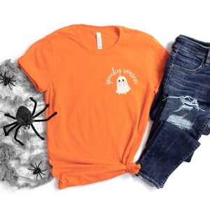 May include: Orange t-shirt with a white ghost graphic and the text "spooky season".