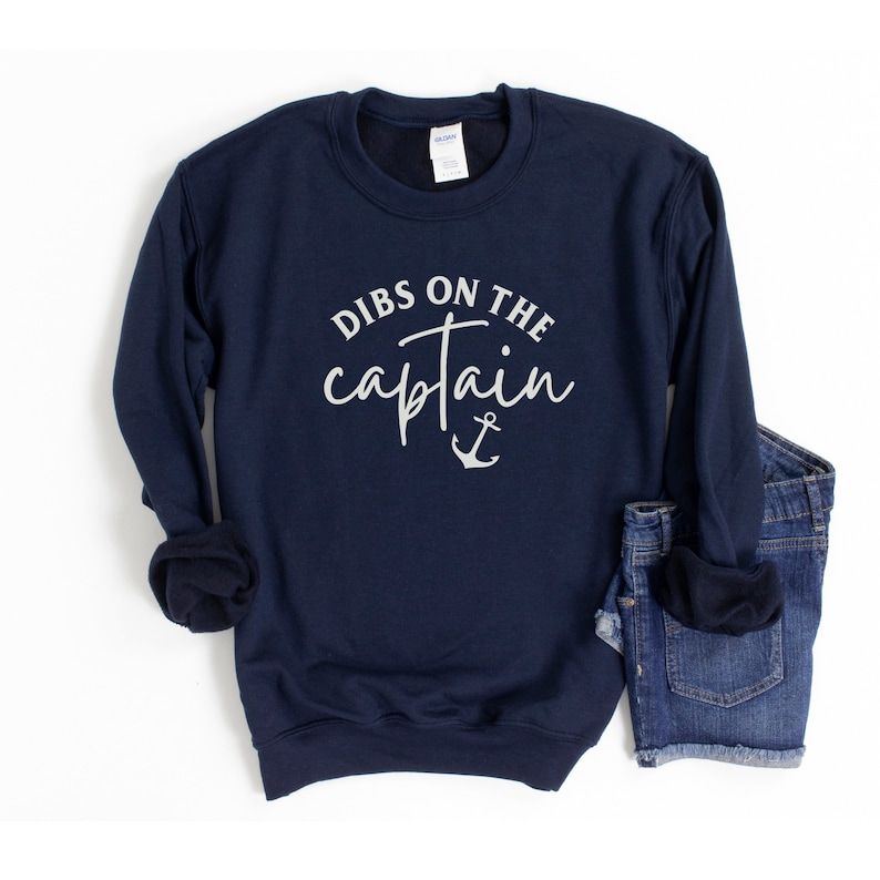 Puede incluir: Sudadera azul marino con el texto "Dibs on the captain" y un gr&aacute;fico de ancla en blanco.