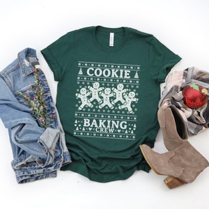 May include: A green t-shirt with a white design featuring gingerbread men and the text "Cookie Baking Crew".
