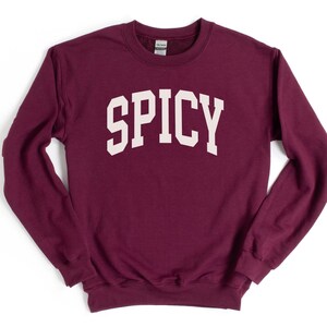 K&ouml;nnte beinhalten: Ein maroonfarbener Pullover mit dem Wort "SPICY" in wei&szlig; auf der Vorderseite.