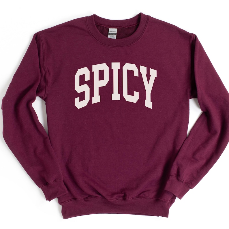 K&ouml;nnte beinhalten: Ein maroonfarbener Pullover mit dem Wort "SPICY" in wei&szlig; auf der Vorderseite.
