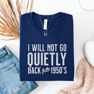 May include: A navy blue t-shirt with white text that reads "I will not go quietly back to the 1950's".