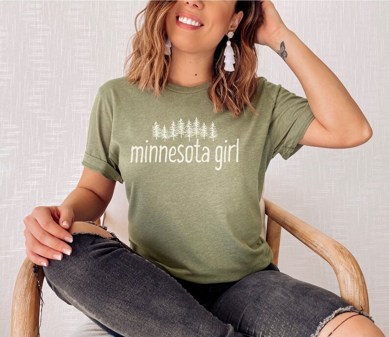 May include: A green t-shirt with a white graphic of pine trees and the text "minnesota girl".