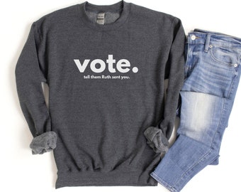 May include: A dark gray sweatshirt with the word "vote." printed in white. Below the word is the text "tell them Ruth sent you."