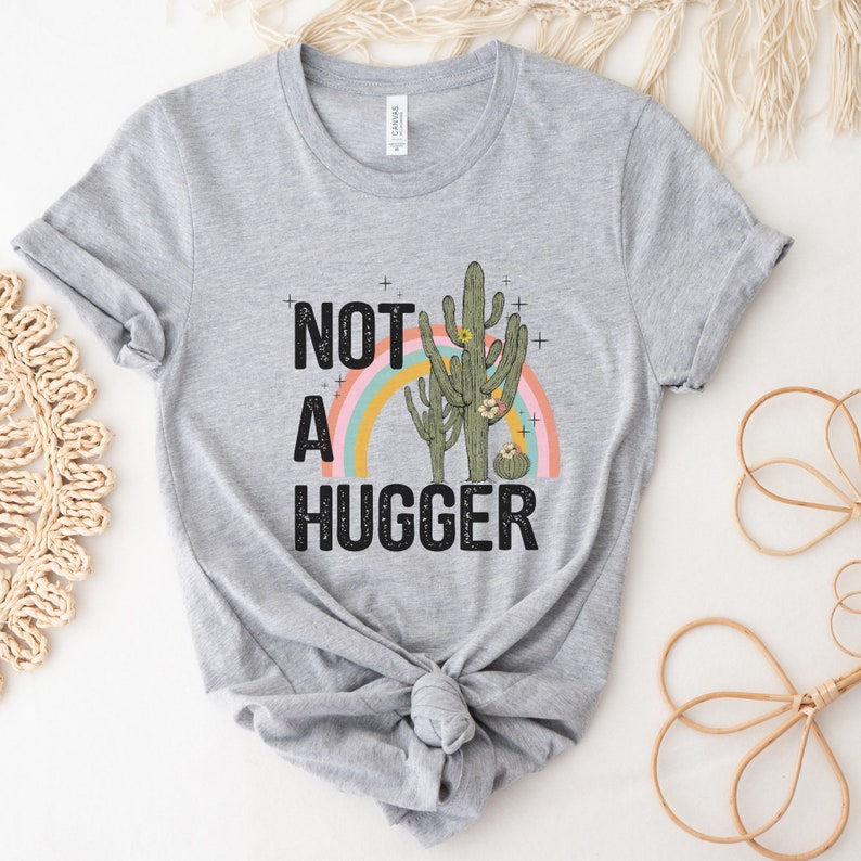 May include: Gray t-shirt with a graphic of two cacti and a rainbow with the text "Not a Hugger" printed on it.