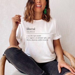 May include: White t-shirt with the word "liberal" defined as "one who is open-minded" and "a supporter of individual rights, civil liberties, democracy, and free enterprise."