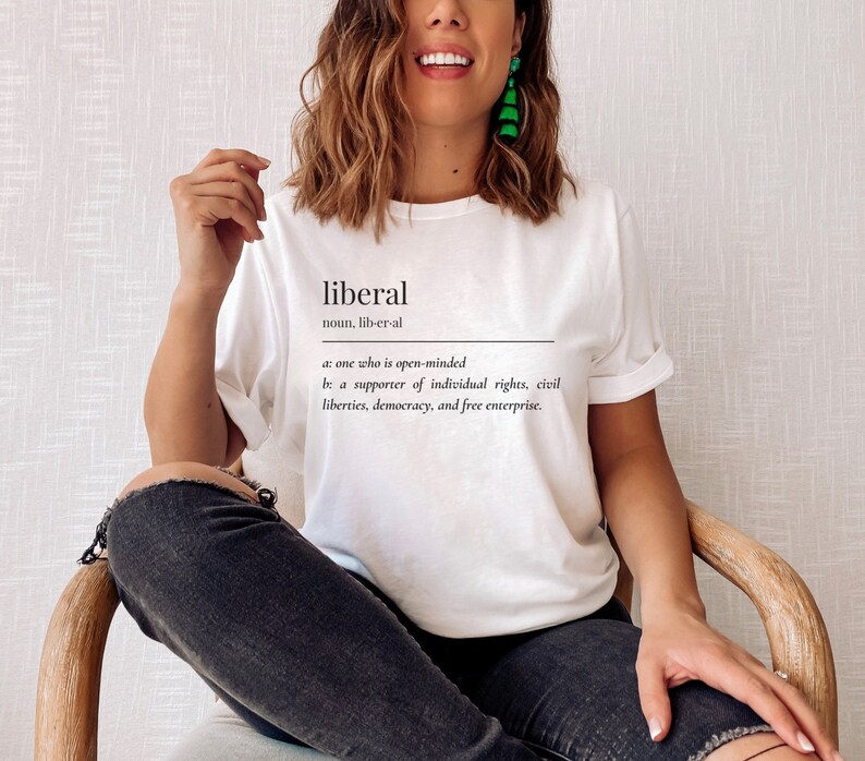 May include: White t-shirt with the word "liberal" defined as "one who is open-minded" and "a supporter of individual rights, civil liberties, democracy, and free enterprise."