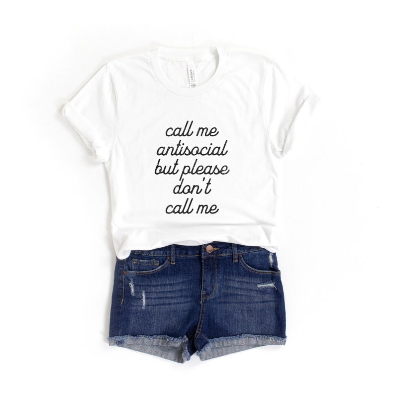 May include: White t-shirt with black text that reads "call me antisocial but please don't call me". The shirt is paired with denim shorts.