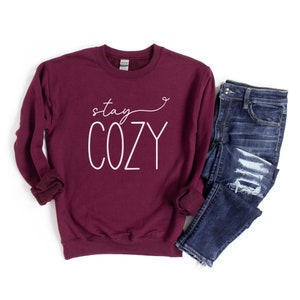 May include: A maroon sweatshirt with the text "stay cozy" in white script lettering.