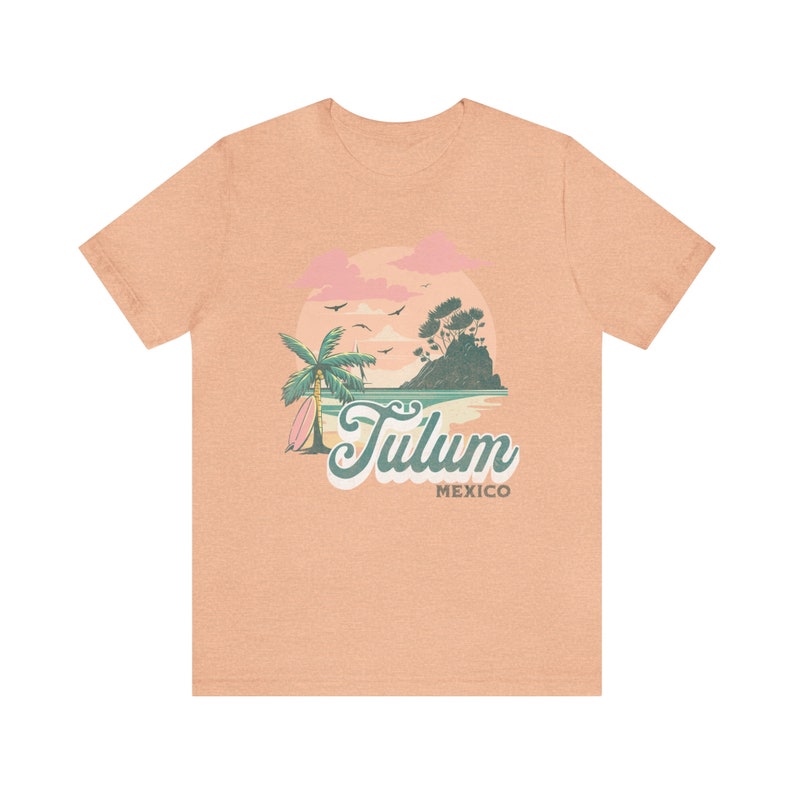 May include: A light peach t-shirt with a graphic of a palm tree, a surfboard, and a sunset over a small island. The text "Tulum Mexico" is printed below the graphic.
