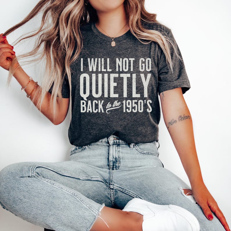 May include: A dark grey t-shirt with white text that reads "I will not go quietly back to the 1950's".