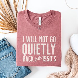 May include: A pink t-shirt with the text "I will not go quietly back to the 1950's" printed on it.