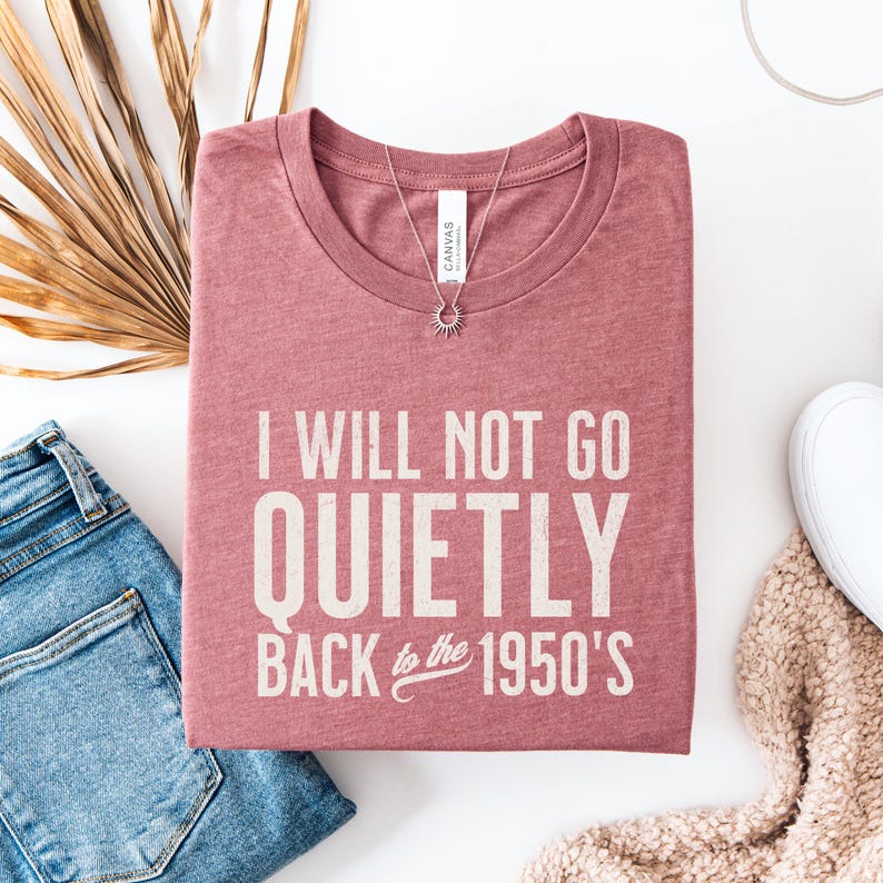 May include: A pink t-shirt with the text "I will not go quietly back to the 1950's" printed on it.