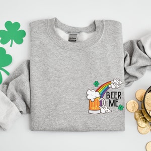 May include: A gray sweatshirt with a graphic of a beer mug with a rainbow and the text "Beer Me".
