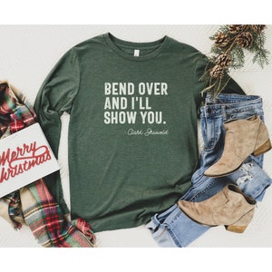 May include: A green long-sleeved t-shirt with the text "Bend over and I'll show you." - Clark Griswold.
