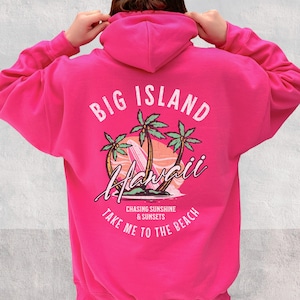 May include: Pink hoodie with a graphic print of palm trees, a surfboard, and the text "Big Island Hawaii Chasing Sunshine & Sunsets Take Me To The Beach".