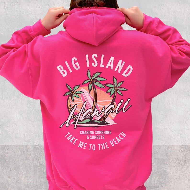 May include: Pink hoodie with a graphic print of palm trees, a surfboard, and the text "Big Island Hawaii Chasing Sunshine & Sunsets Take Me To The Beach".