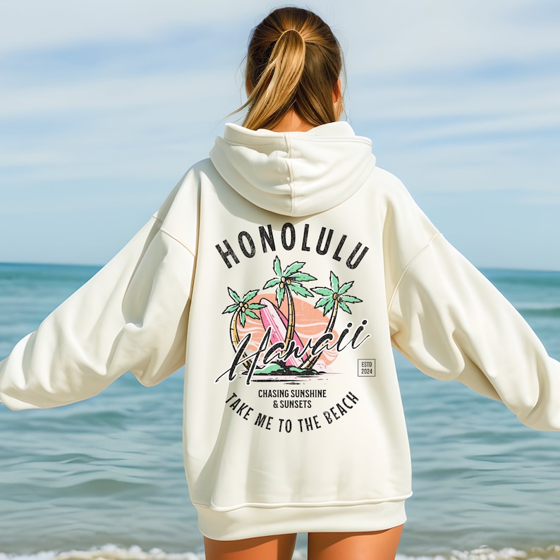 May include: A white hoodie with a graphic print on the back. The graphic features palm trees, a surfboard, and the text "Honolulu Hawaii" with the words "Chasing Sunshine & Sunsets Take Me To The Beach" below.