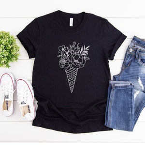 May include: Black t-shirt featuring a white outline of a bouquet of flowers in an ice cream cone.