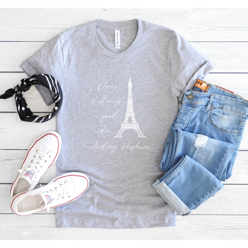 K&ouml;nnte beinhalten: Ein graues T-Shirt mit einem wei&szlig;en Aufdruck des Eiffelturms und dem Zitat "Paris ist immer eine gute Idee - Audrey Hepburn".