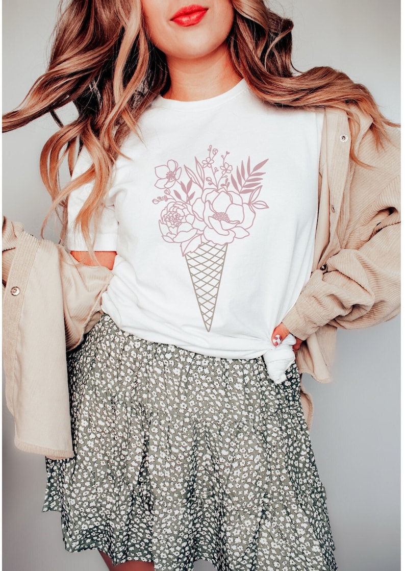 May include: A white t-shirt with a pink floral design in the shape of an ice cream cone.