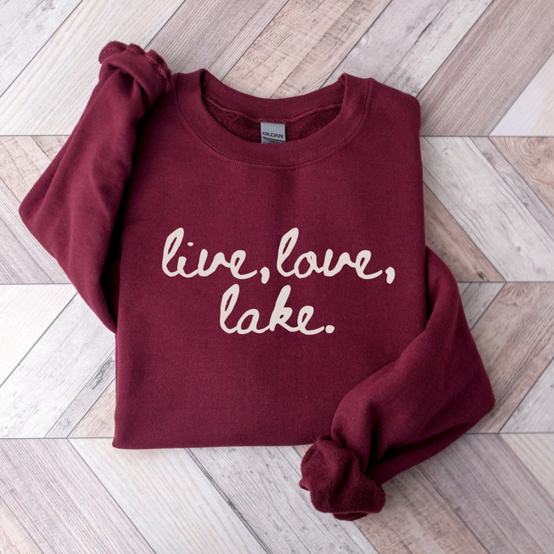 May include: Burgundy sweatshirt with the text "live, love, lake." in white.