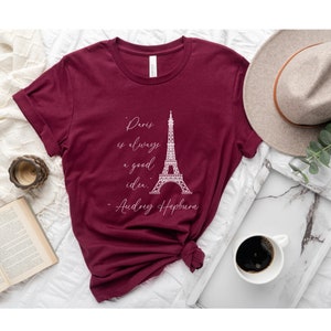 K&ouml;nnte beinhalten: Burgunderfarbenes T-Shirt mit einer wei&szlig;en Grafik des Eiffelturms und dem Zitat "Paris ist immer eine gute Idee. - Audrey Hepburn".