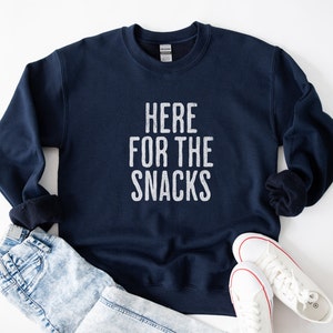 May include: A navy blue sweatshirt with the text "HERE FOR THE SNACKS" printed in white on the front.
