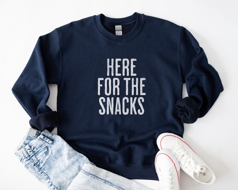 May include: A navy blue sweatshirt with the text "HERE FOR THE SNACKS" printed in white on the front.