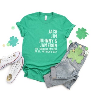 May include: Green t-shirt with white text that reads "Jack Jim Johnny & Jameson The Founding Fathers of St. Patrick's Day".