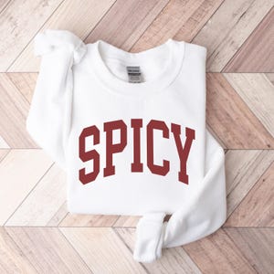 K&ouml;nnte beinhalten: Wei&szlig;er Pullover mit dem Wort "SPICY" in Rotbraun bedruckt.