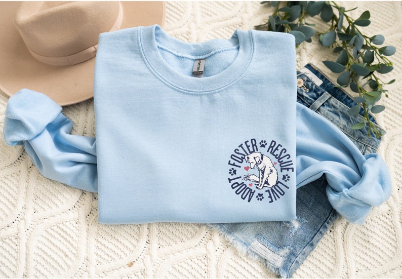 May include: Light blue sweatshirt with a graphic of a dog and the text "Foster Adopt Rescue Love" in a circle.