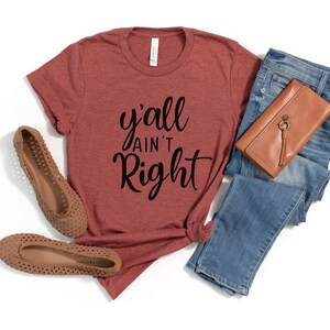 May include: A maroon t-shirt with the text "y'all ain't right" in black cursive lettering.