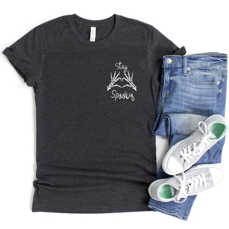 May include: A dark gray t-shirt with a white graphic of skeleton hands making a heart shape with the text "Stay Spooky" on the front.
