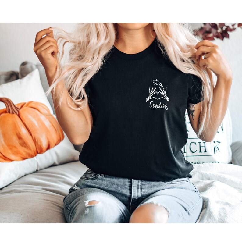 May include: Black t-shirt with a white graphic of two skeleton hands making a heart shape with the text "Stay Spooky".