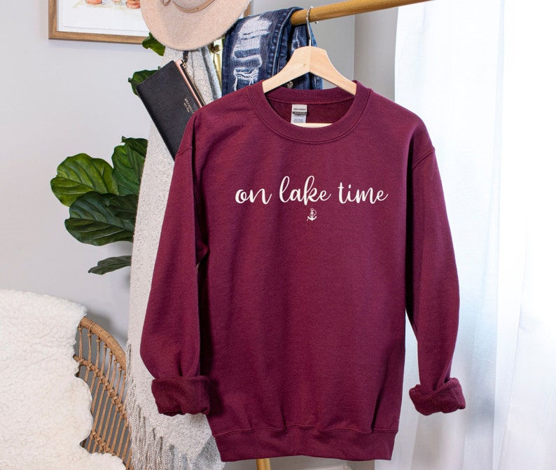 Puede incluir: Sudadera color burdeos con texto blanco que dice "on lake time" y un peque&ntilde;o s&iacute;mbolo de ancla.
