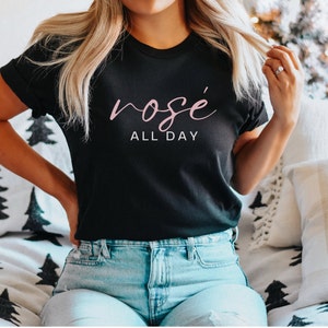 May include: A black t-shirt with the text "ros&eacute; all day" in pink lettering.