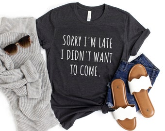 May include: A dark gray t-shirt with the text "Sorry I'm late I didn't want to come." printed in white.